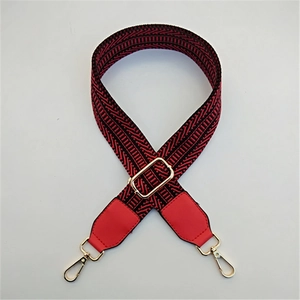 Close-up of red and black herringbone pattern bag strap with gold metal swivel clasps