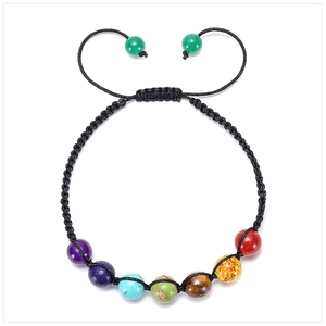Flat lay of colorful 7 chakra gemstone beads on a black woven adjustable energy bracelet