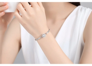 Macro shot of a silver bracelet featuring a circular micro-paved zircon charm on a model's wrist