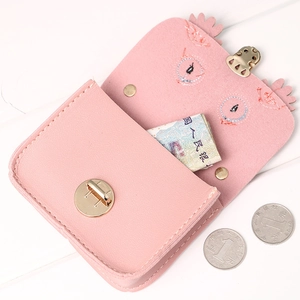 Pink cat-ear shaped PU leather mini wallet with a round metal swivel clasp on wood