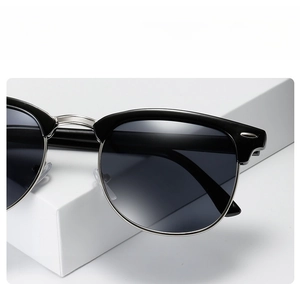 Detail view of retro half-frame sunglasses with silver rivets and gradient grey lenses