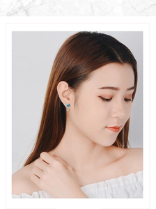 Detail of blue and white star stud earrings worn by a model on a white background