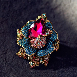 Macro shot of vintage floral brooch with magenta crystal and navy blue pavé stones