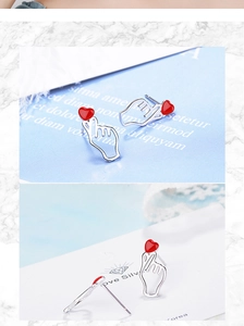 Detail view of silver heart gesture stud earrings with red epoxy heart on card