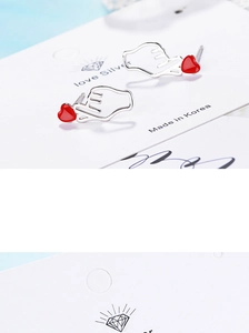 Close-up of heart gesture silver stud earrings with red heart tips on a love display card