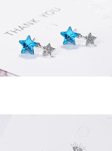 Macro shot of blue star stud earrings with silver crystals on a white card background