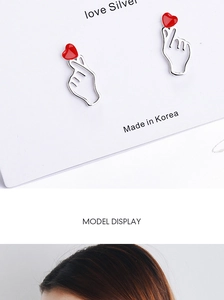 Detailed close-up and model wearing cute red heart gesture earrings in silver finish