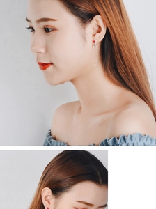 Detailed view of red heart stud earrings in minimalist style on a model ear