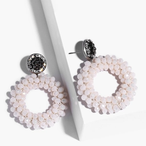 Detailed shot of bohemian white beaded hoop earrings with rhinestone studs on a geometric stand
