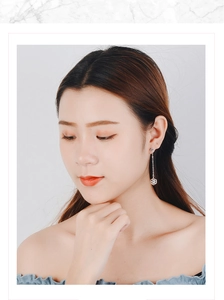 Close-up of elegant silver long tassel earrings with geometric cube charms on model