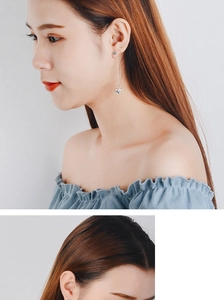 Detail of silver long drop earring with hollow cube pendant on model for elegant style