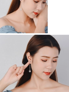 Long silver geometric cube drop earrings displayed on a model in a professional studio setting
