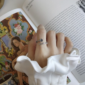 Detail of vintage 925 sterling silver rose thorn ring worn on a hand over an art book