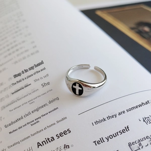 Macro view of S925 sterling silver ring featuring a black cross emblem on book pages