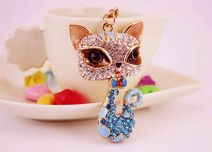Close-up of a sparkling blue enamel cat keychain with white rhinestones and gold base