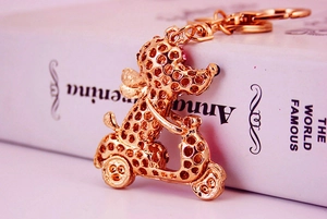 Detail of rose gold rhinestone dog on scooter keychain with hollow texture and lobster clasp