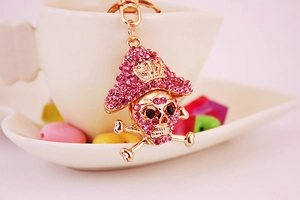 Macro shot of pirate skull keychain with pink crystals on gold metal surface