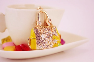 Detailed view of golden handbag keychain with rhinestones and yellow enamel flower
