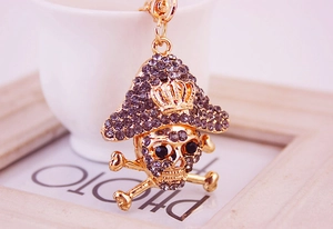 Macro detail of golden pirate skull keychain with embedded dark rhinestones and black gems