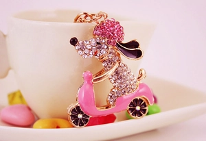 Detail view of sparkling crystal dog on pink motorcycle keychain with metallic gold finish