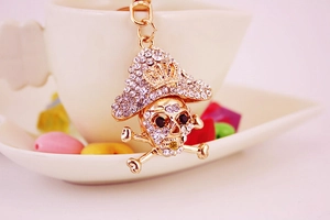 Close-up of gold pirate skull keychain with sparkling rhinestones and crown detail