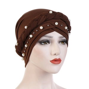 Macro detail of brown turban hat featuring hand-braided knot and white pearl embellishments