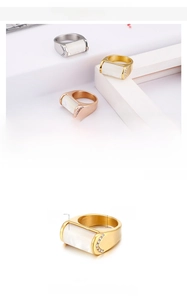 Detail of wide stainless steel rings featuring white shell inlay and zircon accents