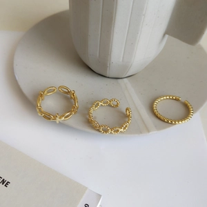 Detailed view of three gold-plated adjustable rings with twisted and beaded textures