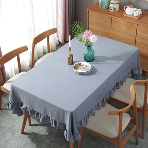 Blue ruffled rectangle tablecloth on a wooden dining table in a cozy home setting