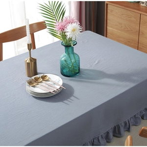 Detail of grey-blue linen tablecloth with ruffled edge on a decorated wooden table