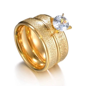 Détail de bagues de couple dorées à texture sablée et incrustation de zircon rond