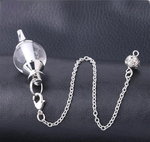 Detailed view of crystal pendant with silver chain and intricate hollow metal sphere
