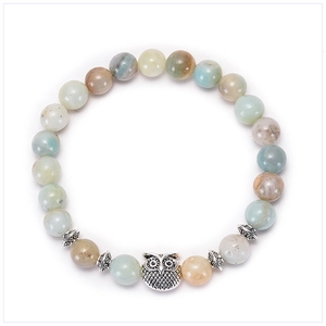 Macro detail of natural stone beaded bracelet featuring a vintage silver owl pendant