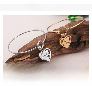 Detailed view of gold and silver heart charms with Love engraving on stainless steel bangles
