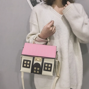 Sac bandoulière rose en forme de maison avec fermoir en métal porté par un mannequin