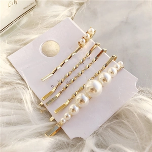 Detail of 5-piece gold hair clip set with faux pearls and geometric wavy hairpins