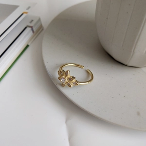 Macro view of gold flower ring with purple and clear zircon stones on ceramic plate