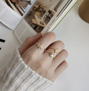 Close-up of gold geometric rings and flower ring with zircons on a model hand