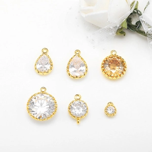 Detail of amber and clear glass jewelry pendants with gold metal bases for DIY crafts