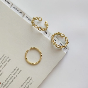 Three-piece stackable gold twisted rings for women on an artistic book background