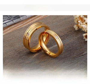 Close-up of gold-plated couple rings with sparkling zircon inlay and textured lines