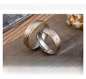 Detail view of brushed steel and gold wedding rings with three inlaid zircons