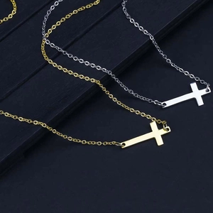 Vue rapprochée des pendentifs croix horizontaux en or et argent sur colliers en acier inoxydable
