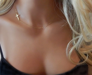 Détail d'un collier croix doré minimaliste porté avec élégance sur le cou d'un mannequin