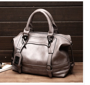 Close-up of grey leather Boston bag with black hardware on a wooden background