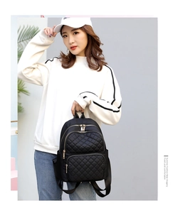 Close-up of a stylish black nylon quilted backpack with elegant gold zippers and hardware