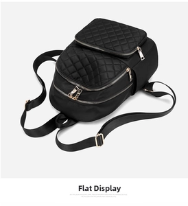 Detailed top view of black quilted nylon backpack with gold zippers and reinforced straps