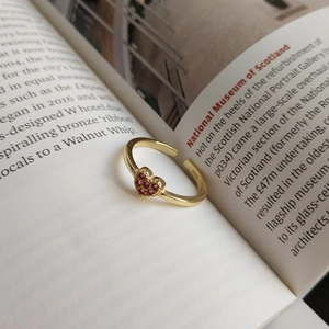 Detail of S925 silver heart ring with purple zircon stones on an open book background