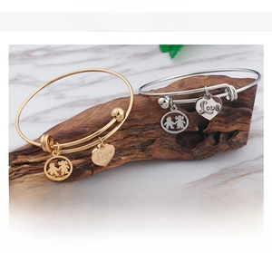 Close-up of minimalist couple bracelets with heart and person charms on wooden base