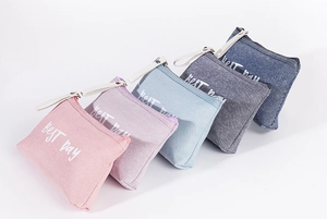 Detail view of multi-color canvas cosmetic zip pouches featuring cute text print for travel storage.